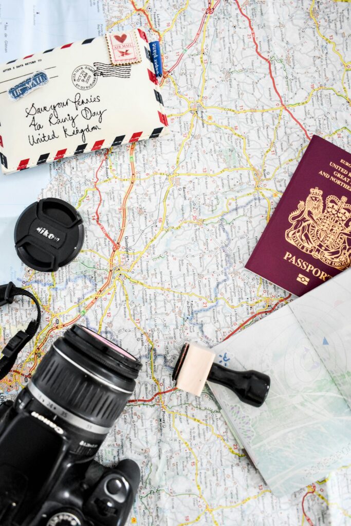 Map, camera and passport laid out on a table for trip planning