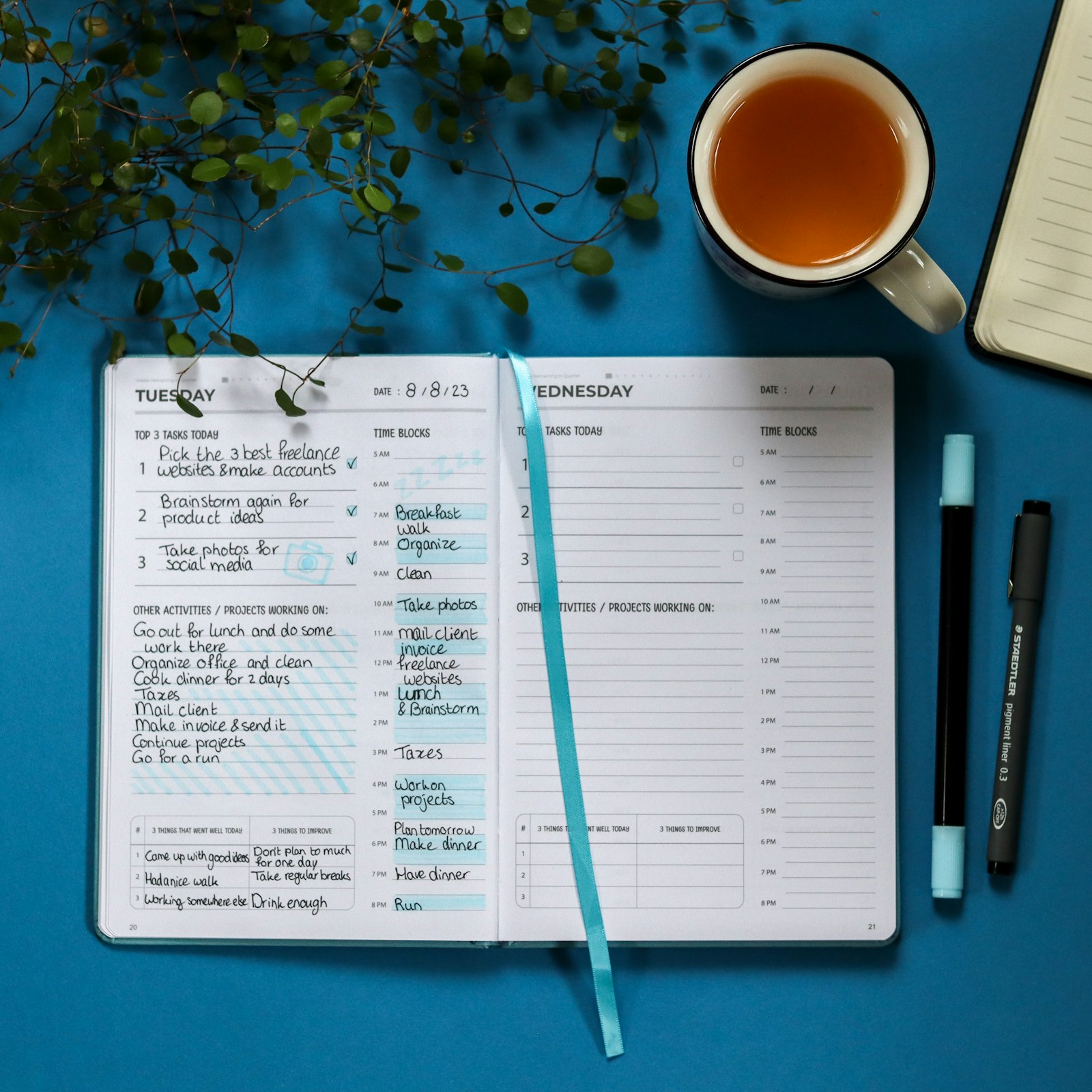 Notebook and planner with a cup of tea, representing small, sustainable wellness habits like an evening brain dump that fit into a busy week