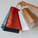 Hand holding colorful shopping bags against a white background